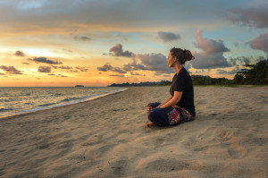 41846180 - woman sitting on beach sand and relaxing at sunset time
